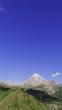 The snow-capped mountains shine against the clear blue sky