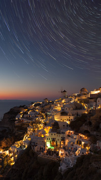 Star trails against moody sky over old town