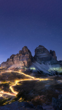 Car light trails on mountain road and high rocks at night
