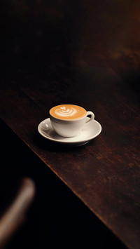 Coffee machiato with latte art on wooden table