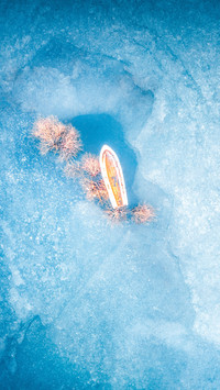 A solitary boat on a frozen lake in stillness.