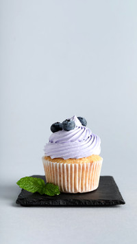 Board of tasty cupcake with blueberries on grey background