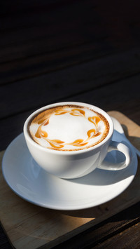 Hot coffee latte art on wooden plate with morning sunlight