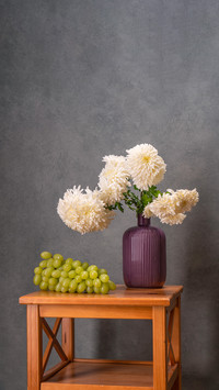 Bouquet of white dahlias in a lilac vase on gray background