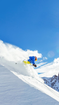 Skier running downhill on piste in Alpine landscape