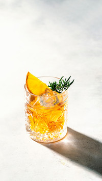 Crystal glass with whisky, rosemary, and orange slice