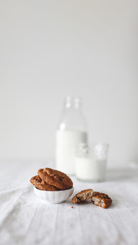 Oatmeal cookies and milk on white table