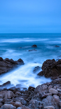 Long exposure of rocks and waves in the Pacific at twilight