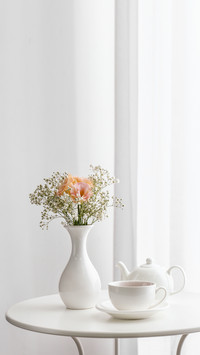 Vase with beautiful flowers and tea on table in room