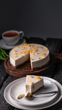 An image of cheesecake on a plate on a dark wooden backdrop
