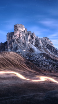 Car light trails on mountain road and high rocks at night