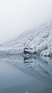 Ice mirror lake reflects snow mountains