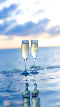 Two glasses of champagne on the side of the infinity pool