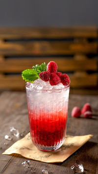 Raspberry cocktail with mint and ice on wooden table
