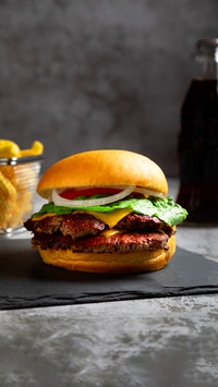A vertical closeup of a delicious cheeseburger on a table
