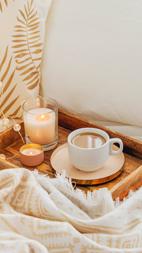 Wooden tray of coffee and candles on bed