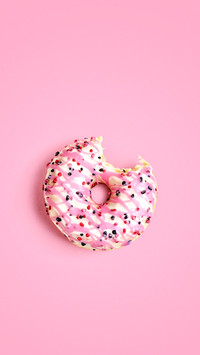 Sweet bitten donut on pink background