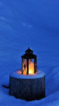 Christmas candle lantern in snow at dusk
