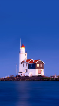 A lighthouse on the beach during blue hour