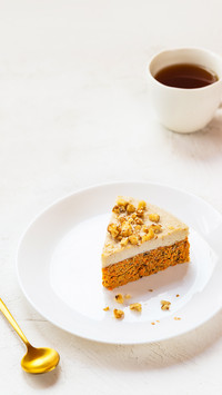 Slice of vegan carrot cake with coconut cream and walnuts
