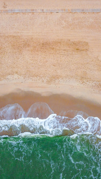 Waves crash against the shore, following each other along.