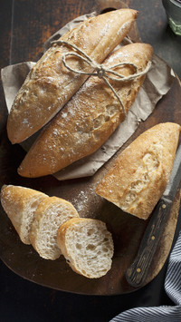Small baguette rolls whole and sliced on a wooden board