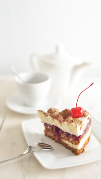Slice of cake decorated with cocktail cherry