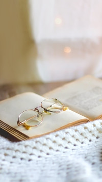 Open book, reading glasses, soft blanket