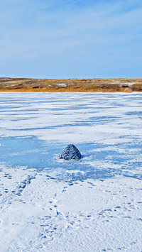 Spring steppe with frozen river and tent for ice fishing
