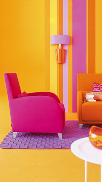 Pink armchair in front of striped wallpaper in living