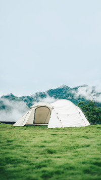 Camping tent in the wilderness on green grass and blue sky