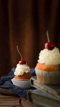 Delicious cupcakes with cream and cherries on top