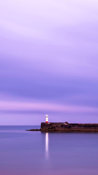 Landscape lighthouse at sunset with calm sea