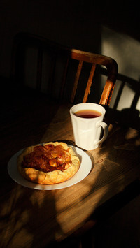Caramelized apple pie on white saucer with a cup of tea