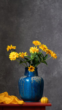 A bouquet of yellow autumn colors in a large blue vase
