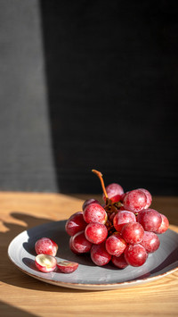 Top view of grapes in gray plate on wooden table
