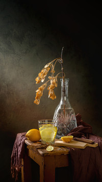 Still life with a cup of water with lemon and a maple branch