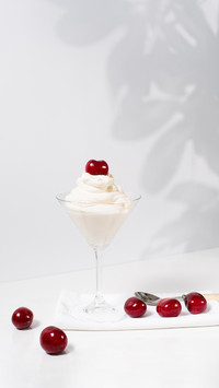 Ice Cream with Sweet Cherries in Cocktail Glass on table