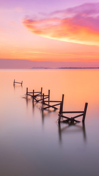 Perspective view of a abandoned wooden pier on sunset