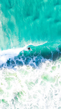 Surfer surfing a wave at sunrise in a blue turquoise ocean
