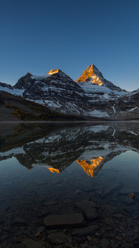 Sunlit Snowy Peak with Mirror-Like Lake Reflection