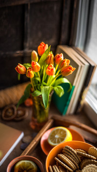 A bouquet of tulips in a vase and tea with lemon