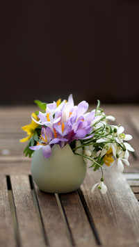 Flowers in vase close up, on wooden table vertical