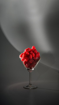 Fresh raspberries in glass beaker on white background