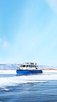 Tourists travel on the ice of a frozen lake Baikal on boats