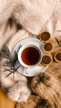 A cup of tea with chopping cookies on piles of sweaters