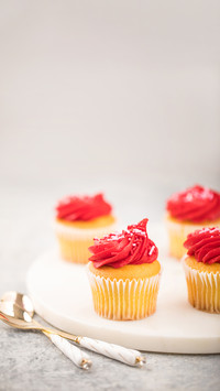 Red frosting Valentines Day cupcakes on white marble tray