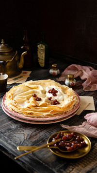 Homemade stack of thin crepes with red jam on plates