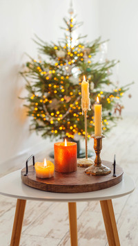 Burning candles on table on background christmas tree