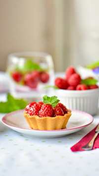 Mini tarts with raspberries served with tea on the table